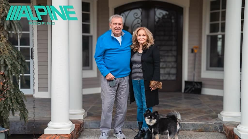 husband and wife in front of home with large porch and puppy