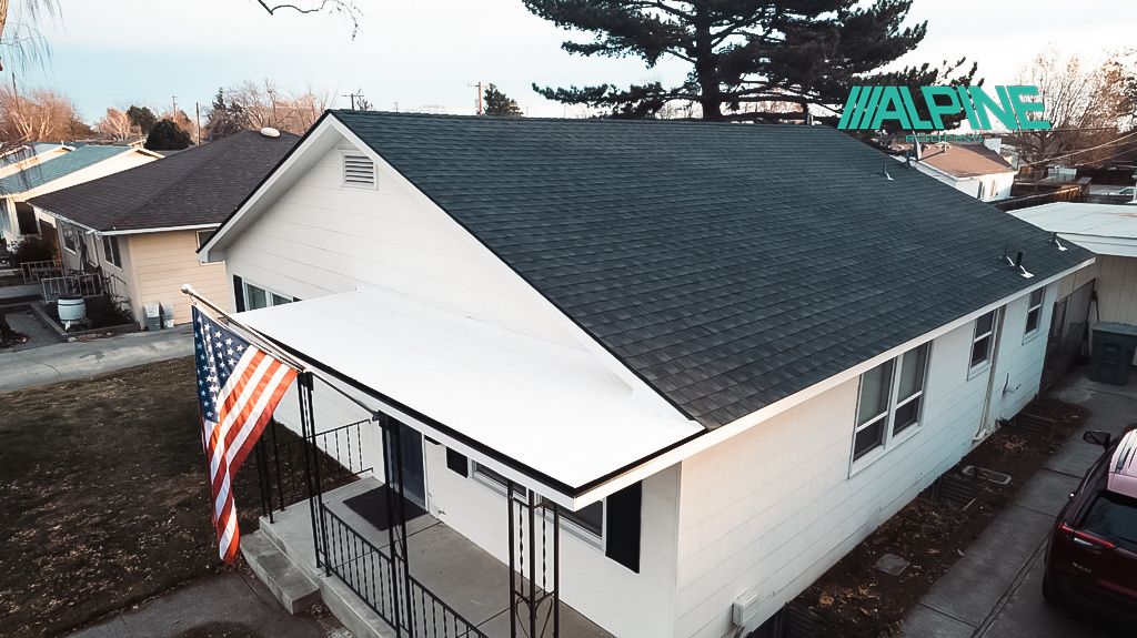 home with white siding and black trim with a black shingle roof and alpine logo on photo