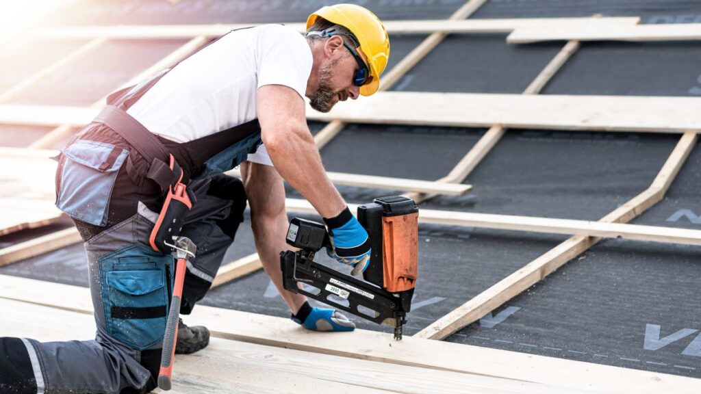 Roofer using nail gun to install roof