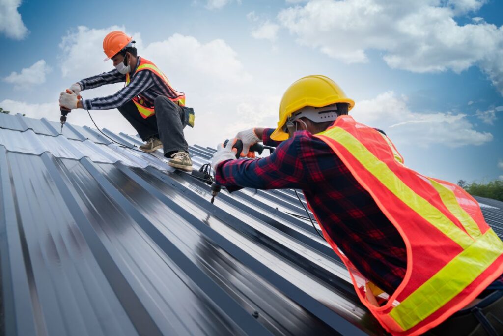 two construction workers installing metal roof