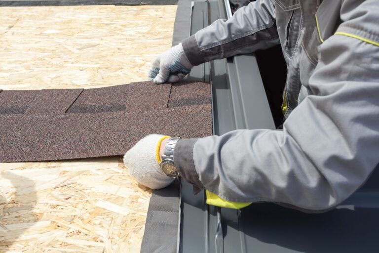 roofer lays asphalt sheet on the rooftop