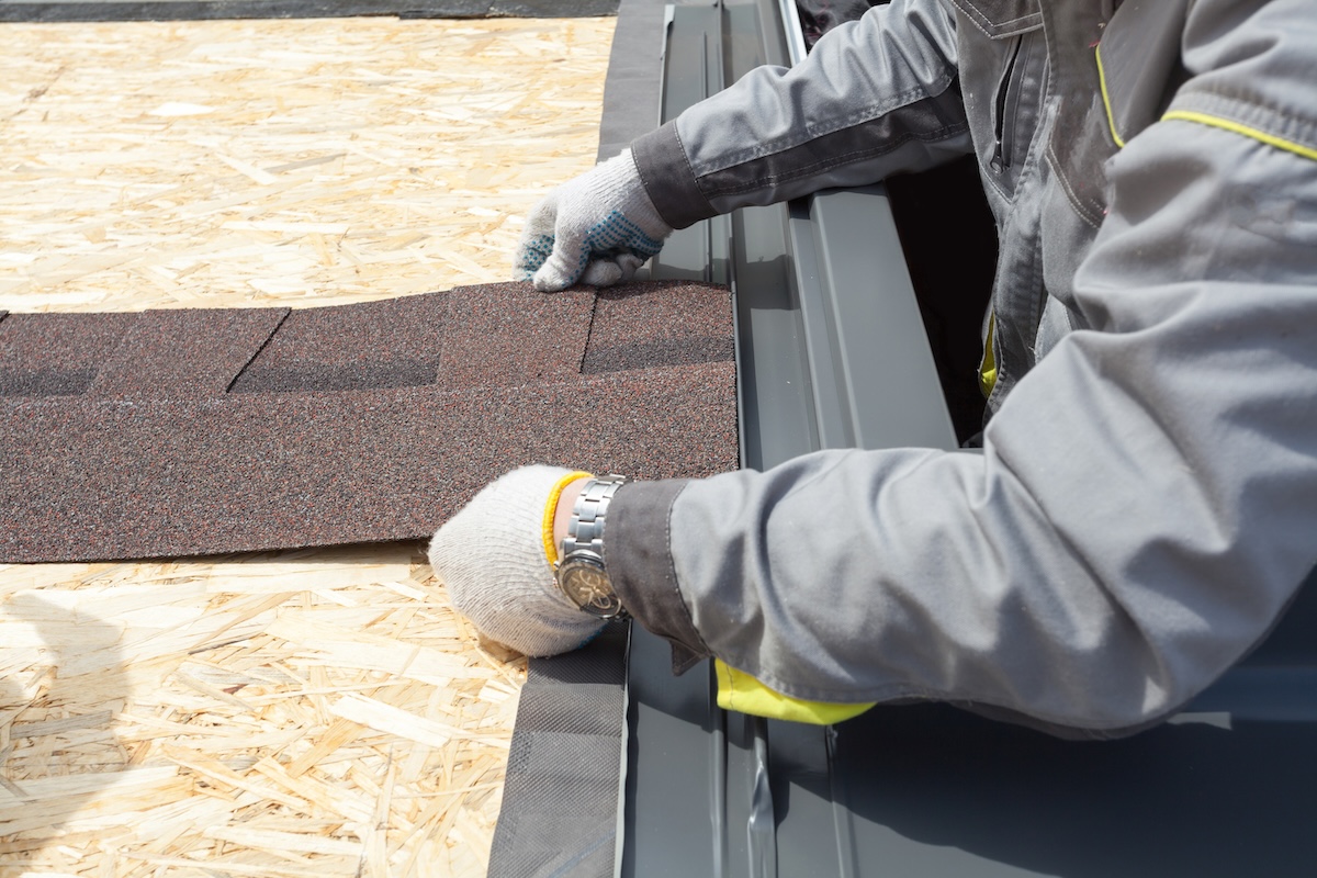 roofer lays asphalt sheet on the rooftop