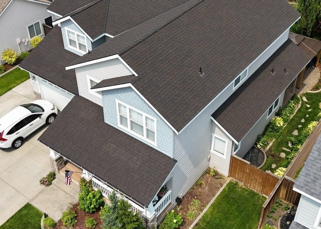 A large house with a dark shingle roof and an American flag