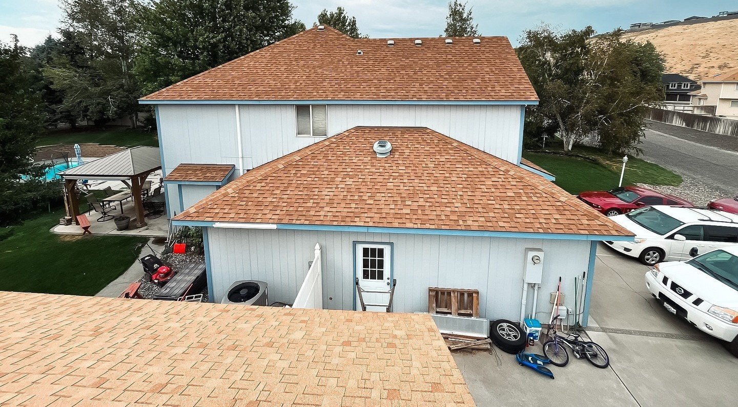 Light brown asphalt shingle roof on a white house