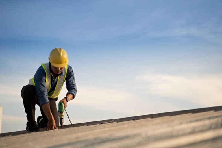 roofing companies in Airway Heights WA worker drilling on top of roof