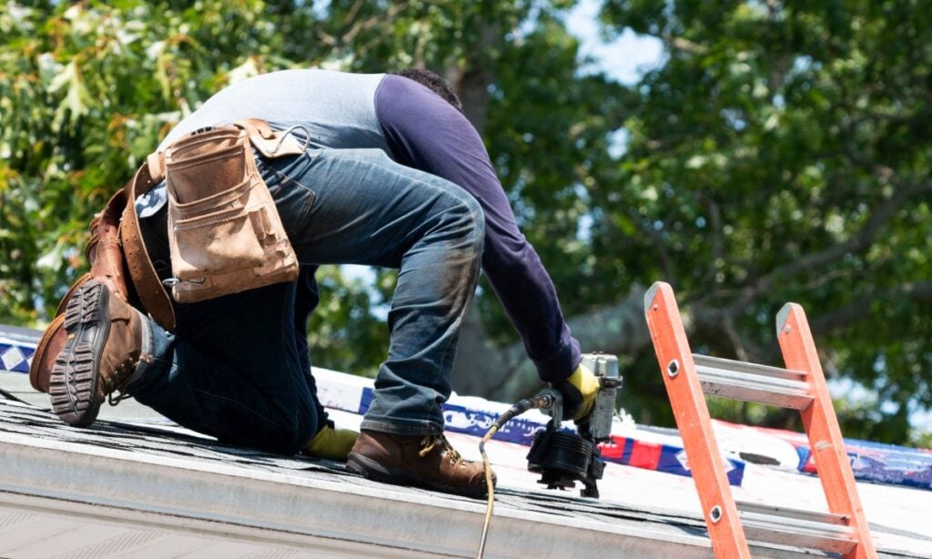 roofing companies in Airway Heights WA worker using nailgun on top of roof